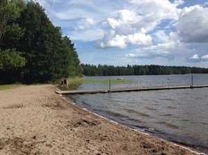 Fin sandstrand med lång brygga. 